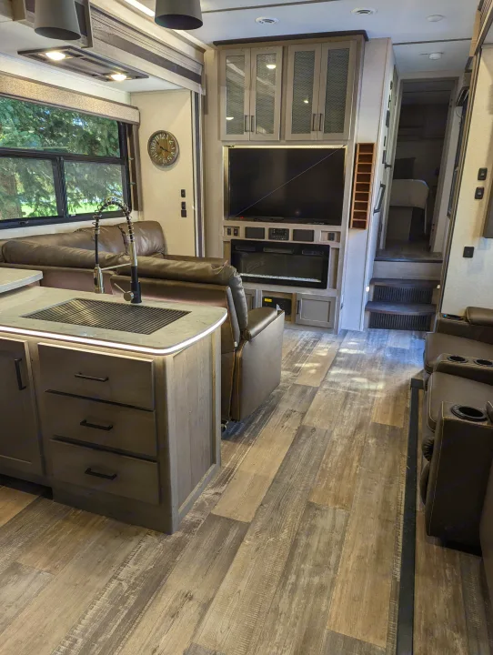 Explore our rv rental's spacious interior: kitchen with sink, cozy living area, TV, and fireplace.. Keystone Raptor 2021