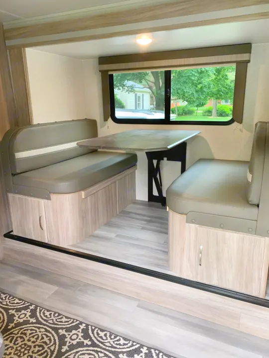 Step inside this cozy RV rental dinette! Features comfortable bench seating, a table, and large window in a compact travel trailer.. Winnebago Micro Minnie 2021