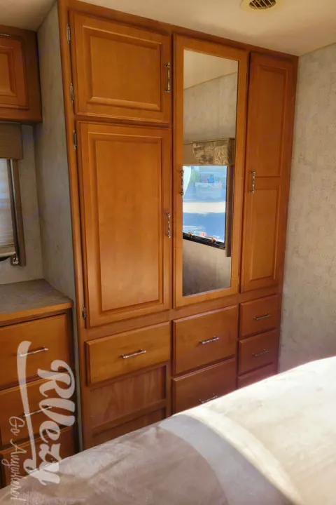 Organized RV rental interior: Light wood overhead cabinets with a mirror, perfect for maximizing storage during travel.. Winnebago Chalet 2007