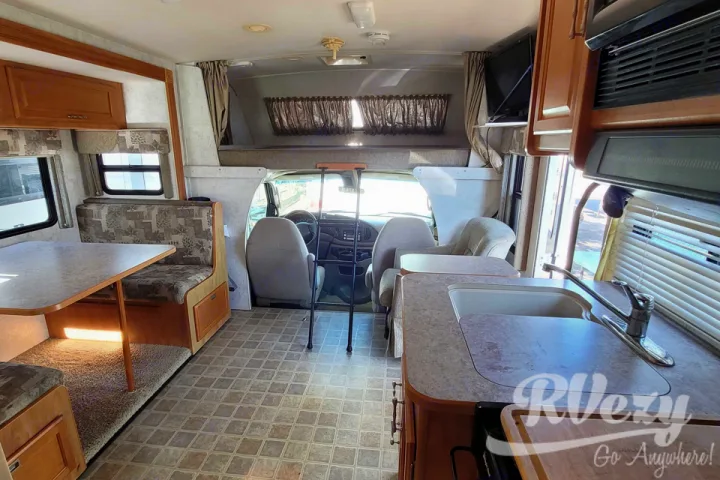 RV rental: Bright interior showing the dinette, kitchen counter with sink, and cab-over bunk. Your adventure awaits!. Winnebago Chalet 2007