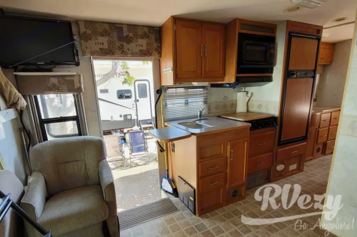 Explore this rv rental's comfy interior: a practical kitchen, relaxing living space, and an open door to nature.. Winnebago Chalet 2007