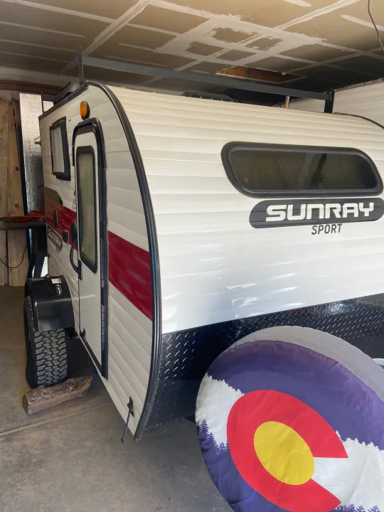 White & red Sunray Sport travel trailer/camper, ideal for RV rental. Features a Colorado spare tire cover.. Sunset Park RV SunRay 2020