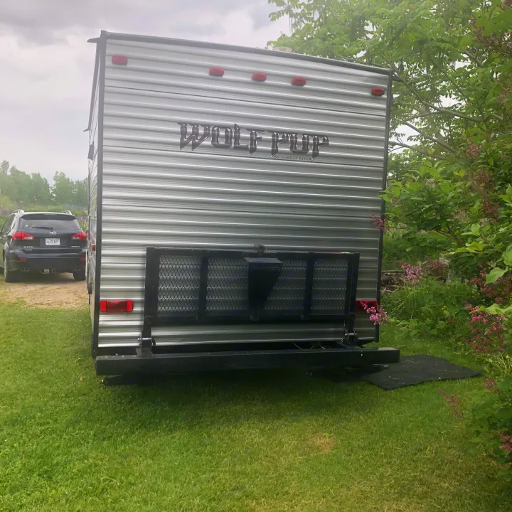 RV rental: Wolf Pup travel trailer with cargo rack parked on green grass near a Subaru and lilac bushes.. Forest River Cherokee 2014