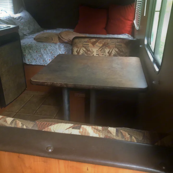 Step inside this cozy RV rental! It features a patterned bed, a dinette with bench seating, and a window for natural light.. Forest River Cherokee 2014