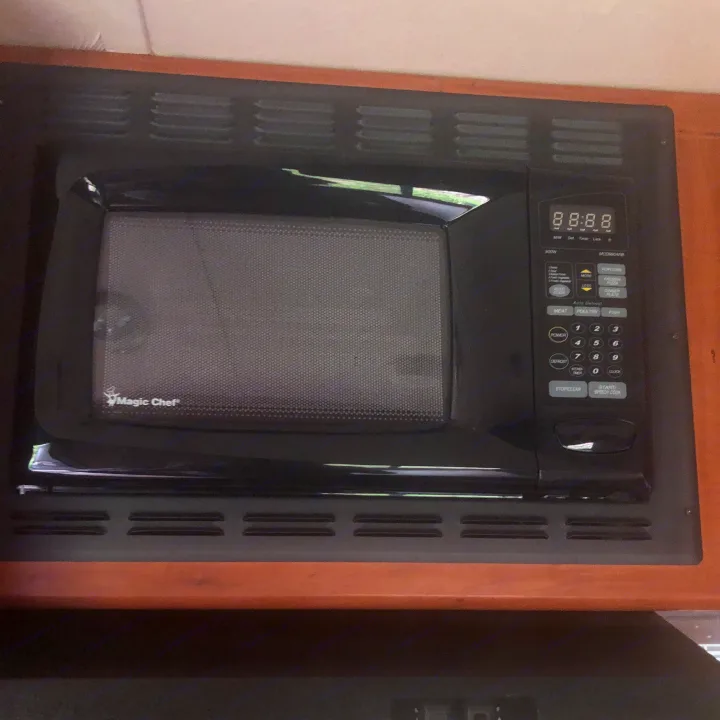Inside an RV rental, a black Magic Chef microwave is built into the cabinetry, featuring a digital display.. Forest River Cherokee 2014