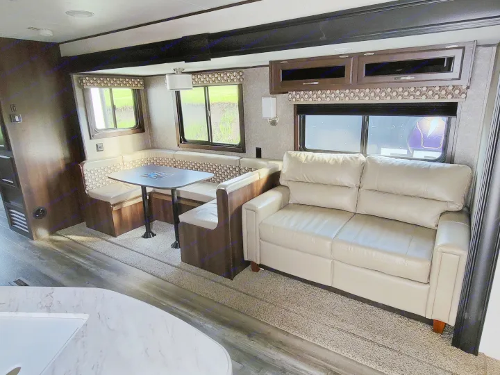 Spacious RV rental interior featuring a dining booth, comfortable sofa, and large windows, ideal for travel.. Jayco Jay Flight 2020