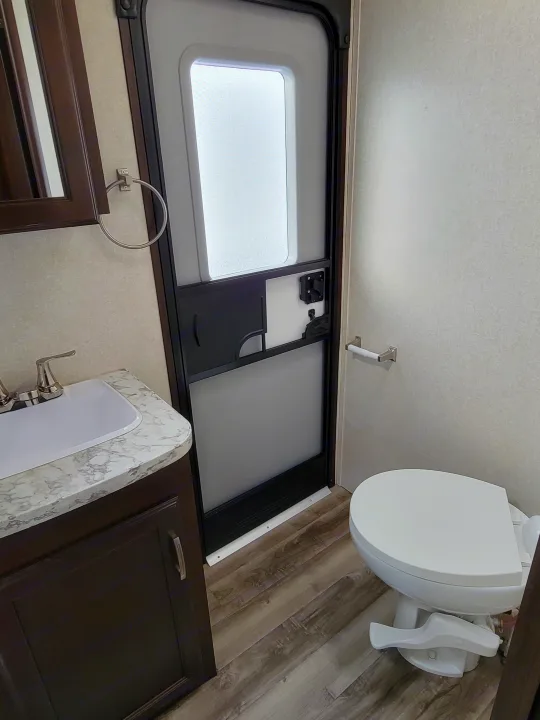 RV rental: Bright, compact bathroom with white toilet, marble-look sink vanity, and sliding window for privacy.. Jayco Jay Flight 2020