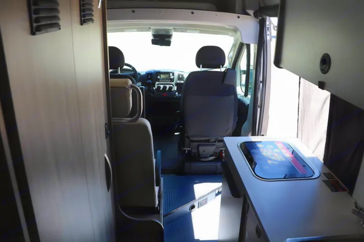 Camper van interior for RV rental. Shows front cabin with dashboard, seats, and a modern digital control panel.. Winnebago Solis 2022