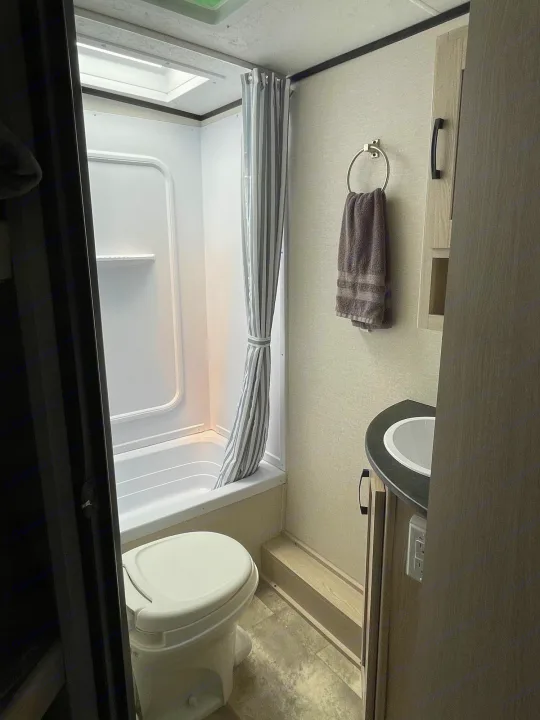 Inside an RV rental bathroom: a cozy setup with shower, tub, toilet, and sink. Compact and functional for travel.. Coachmen Apex 2022