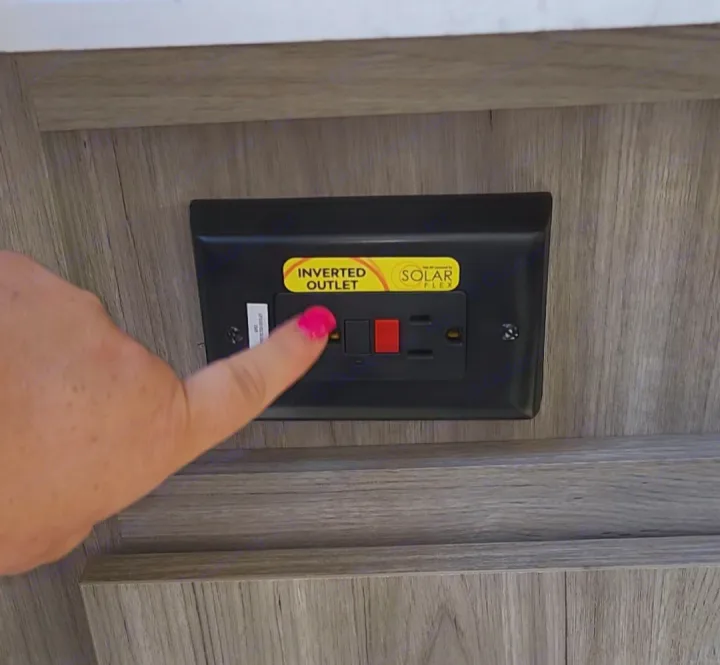 RV rental: A hand points to an "Inverted Outlet" with "Solar Flex" label, common in RV electrical systems.. Keystone RV Passport SL 2022