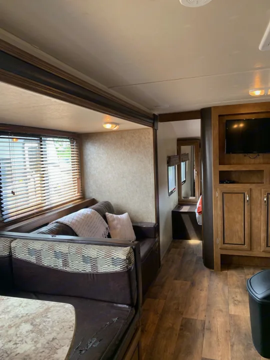 RV rental's cozy interior features a living space with dinette, sofa, TV, and wood-look flooring. Ready for your adventure.. Forest River Wildwood X-Lite 2016
