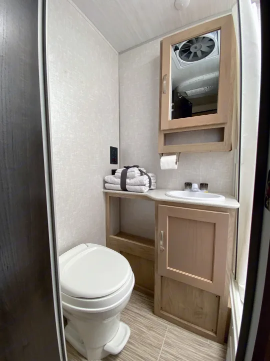 Compact RV rental bathroom with a white toilet, sink, light wood cabinetry, and a mirrored medicine cabinet, ideal for travel.. R-Pod R-Pod Trailer 2021