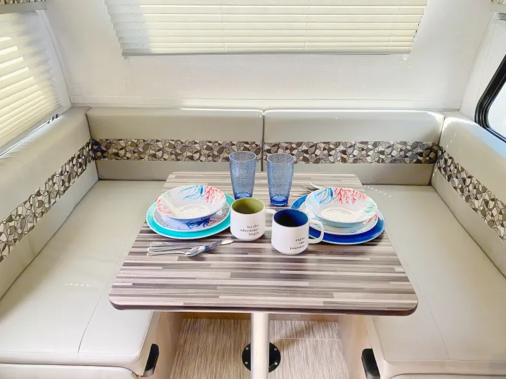 RV rental dinette setup featuring comfortable bench seating with a patterned trim, and a table set for two with colorful dishes.. R-Pod R-Pod Trailer 2021