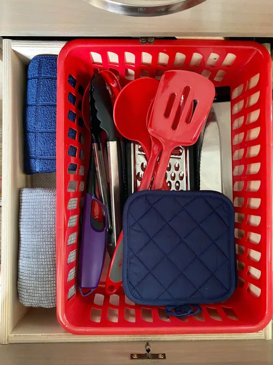 RV rental kitchen drawer: Organized red basket with utensils, towels, lighter, and pot holder.. R-Pod R-Pod Trailer 2021