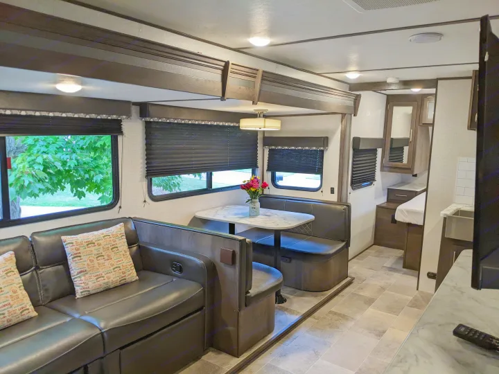 Spacious RV rental interior with a modern design, comfy lounge, dinette, and bright windows showcasing the outdoors.. Dutchmen Coleman Light 2021