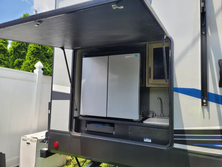 RV rental with an open outdoor kitchen: mini-fridge, sink, and drawer, ready for al fresco dining.. Forest River Cherokee Alpha Wolf 2021