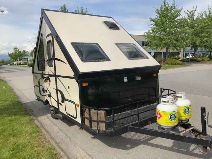 An A-frame Starcraft Comet RV rental, equipped with propane tanks, parked on a street during the day.. Starcraft Comet 2015