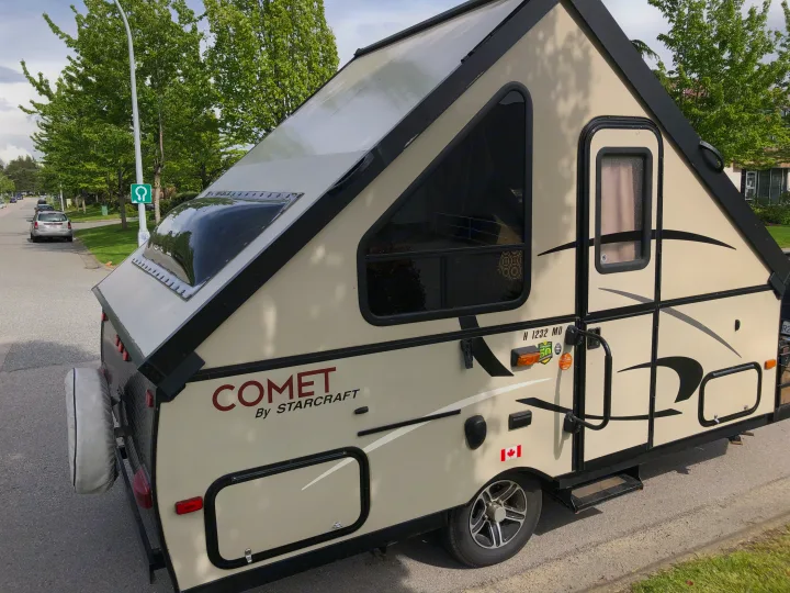 A StarCraft Comet A-frame RV rental is parked curbside. This compact recreational vehicle offers unique travel adventures.. Starcraft Comet 2015