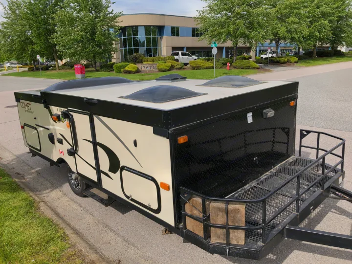 Starcraft Comet travel trailer, a compact pop-up RV rental with a front rack, parked by a building.. Starcraft Comet 2015
