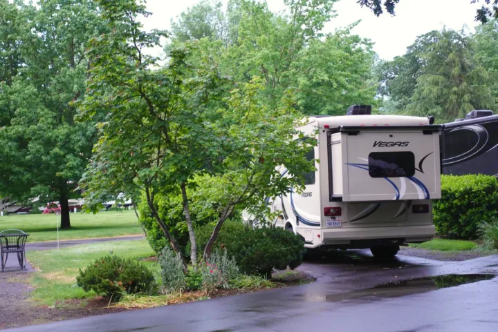 A spacious Vegas motorhome, perfect for an rv rental adventure, parked in a serene, green campground after rain.. Thor Vegas 2017