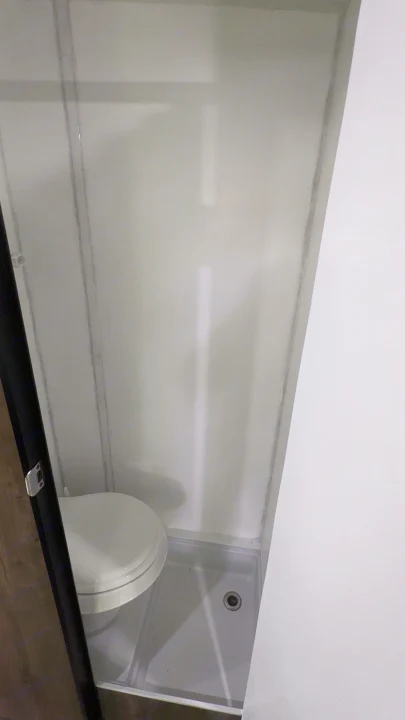 RV rental's compact wet bath with white toilet, shower pan, and light walls. Ideal for travel.. Prolite RV Evasion 16 2022