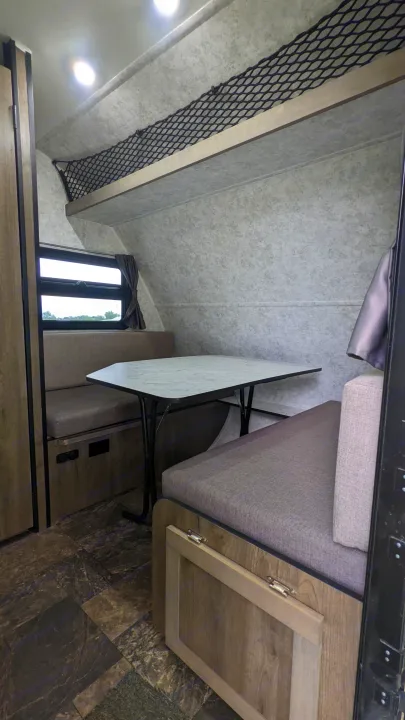 RV rental: Compact dinette with table & bench seating, converts to bed. Overhead storage net visible.. Prolite RV Evasion 16 2022
