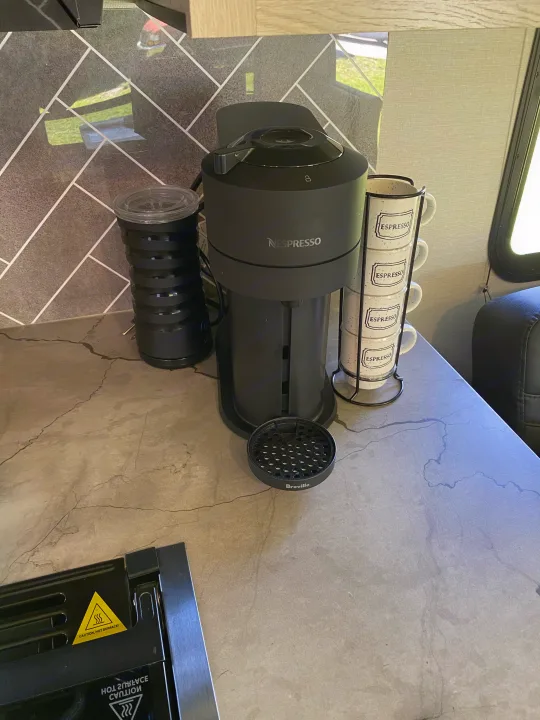 Nespresso coffee machine & frother with espresso cups on a modern countertop in an RV rental kitchen.. Forest River two bedroom Apex ultralite 2022