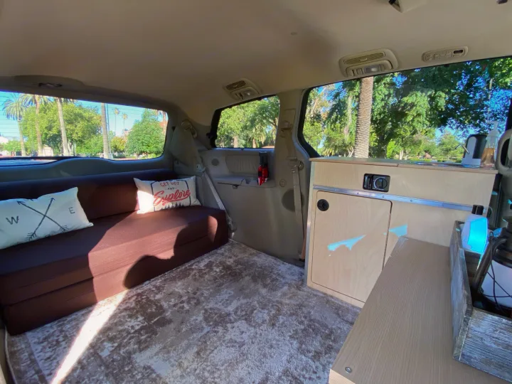 Step inside this RV rental campervan with a comfortable lounge bed, custom cabinetry, and scenic park views.. Custom Camper 2004