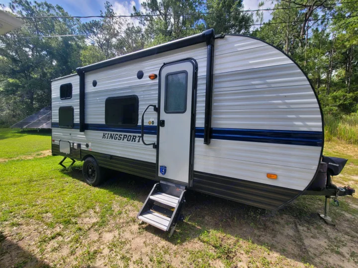 Kingsport RV rental: A sleek white and blue travel trailer with steps, parked outdoors on a sunny day.. Gulf Stream Kingsport 2022