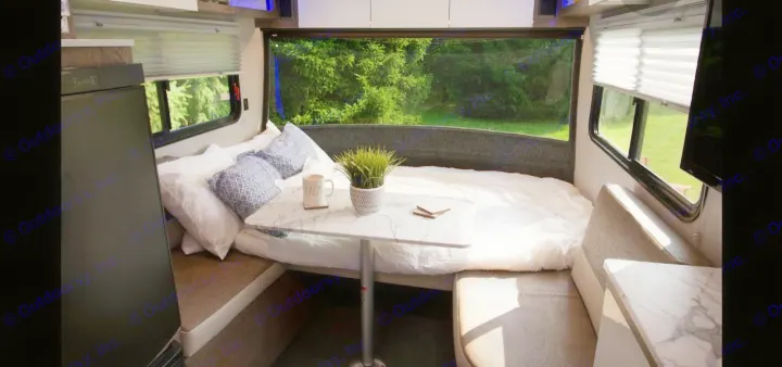 Cozy RV rental interior with a comfortable bed, dinette table, and large window view. Perfect for mobile living.. Intech Sol Horizon Rover 2022