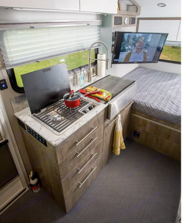 Modern RV rental with a fully equipped compact kitchen (stove, sink, drawers), TV, and comfortable bed for mobile adventures.. Intech Sol Horizon Rover 2022
