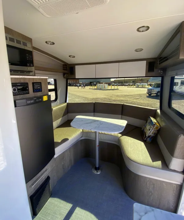Modern RV rental interior: U-shaped dinette, compact kitchen with microwave & fridge, overhead cabinets. Bright, functional space.. Intech Sol Horizon Rover 2022