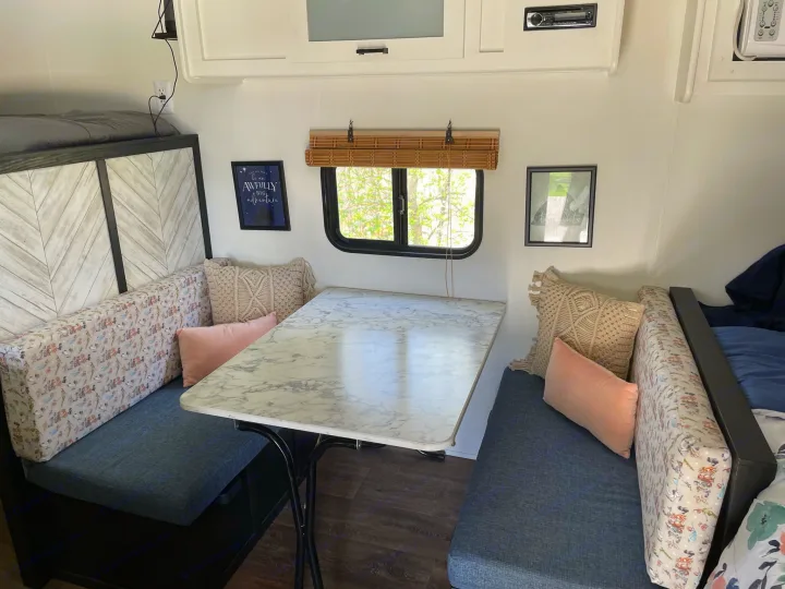 Explore this stylish RV rental dinette featuring comfortable seating, a marble table, and bright decor for your next adventure.. Dutchmen Coleman Lantern LT 2021