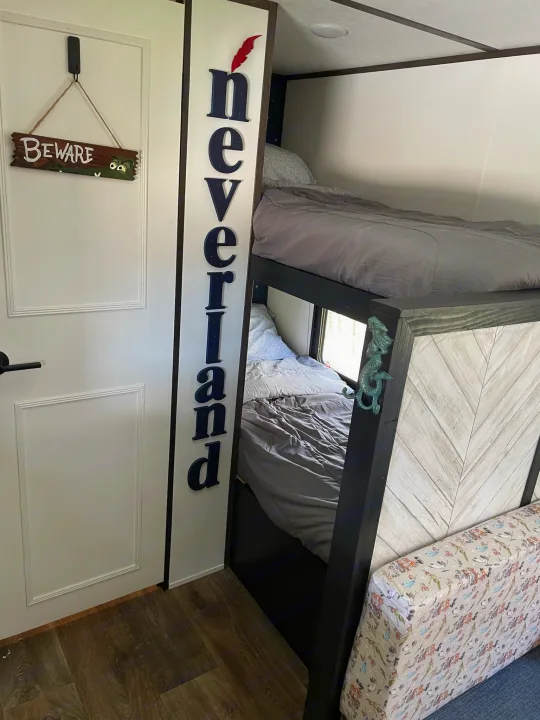 Neverland-themed bunk beds, with a crocodile "Beware" sign and mermaid decor, cozy up this RV rental interior.. Dutchmen Coleman Lantern LT 2021