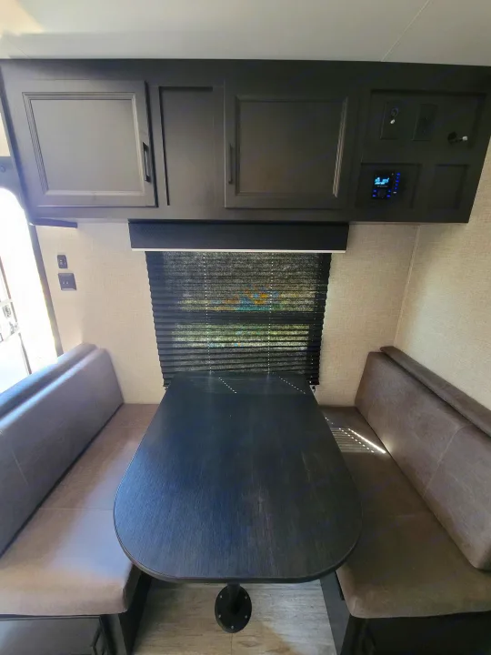 RV rental dinette: a dark table, comfy bench seating, and overhead storage cabinets in a modern interior.. Jayco Jayco Jay Flight SLX 264bhw 2022