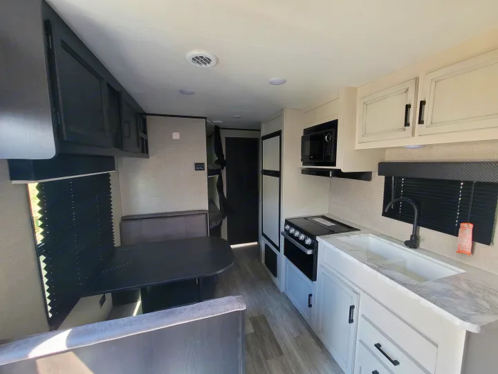 Bright rv rental interior: modern kitchen with sink, stove, microwave, a dining booth, and bunk beds.. Jayco Jayco Jay Flight SLX 264bhw 2022