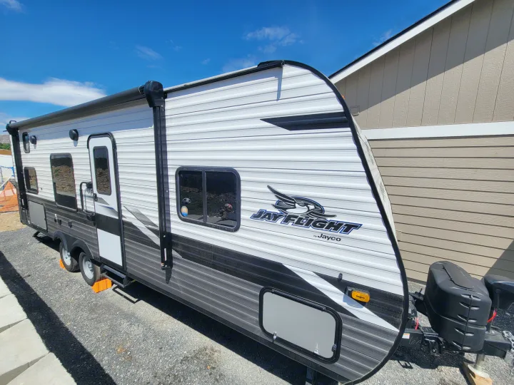 White and gray Jayco Jay Flight RV rental, parked on gravel outside on a sunny day.. Jayco Jayco Jay Flight SLX 264bhw 2022