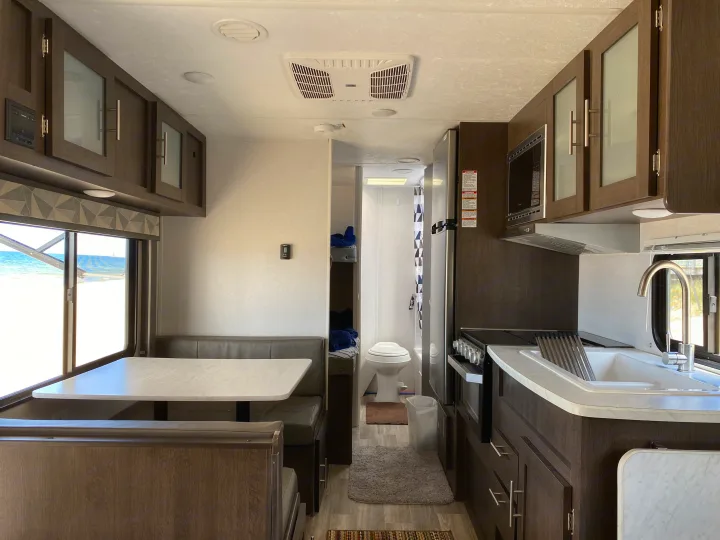Spacious RV rental interior featuring kitchen, dinette, bunk beds, and a bathroom, with an ocean view.. Forest River Wildwood X-Lite 2019