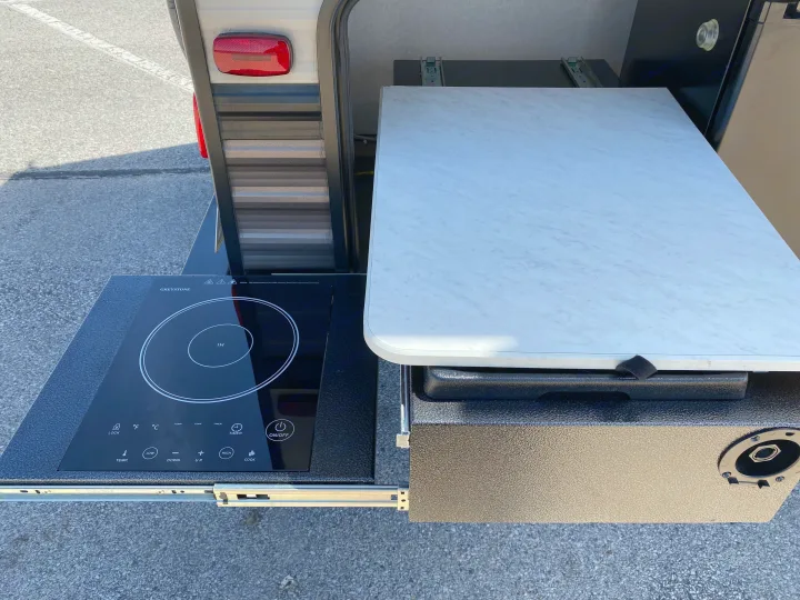 RV rental's pull-out outdoor kitchen: Greystone induction cooktop and prep counter for camping.. Forest River Wildwood X-Lite 2019
