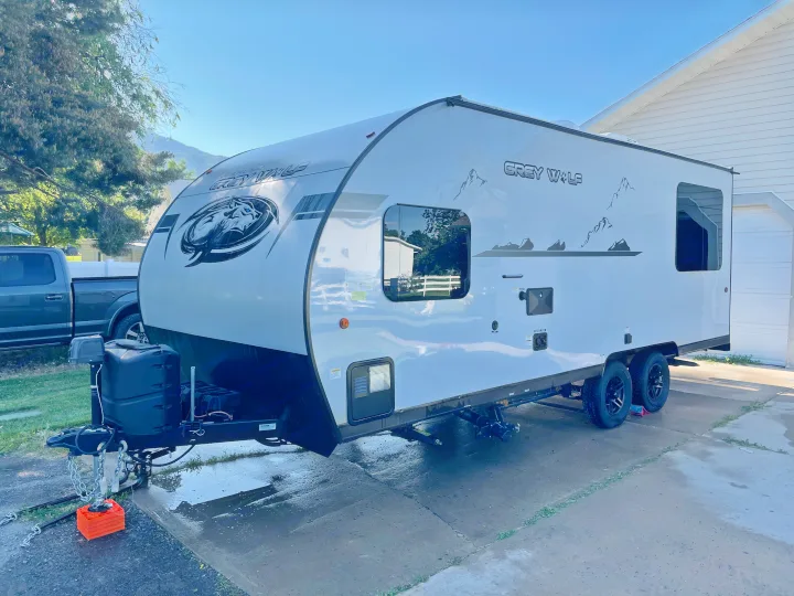Modern Grey Wolf travel trailer, an ideal RV rental, parked on a driveway with a pickup truck in the background.. Forest River Cherokee Grey Wolf 2021