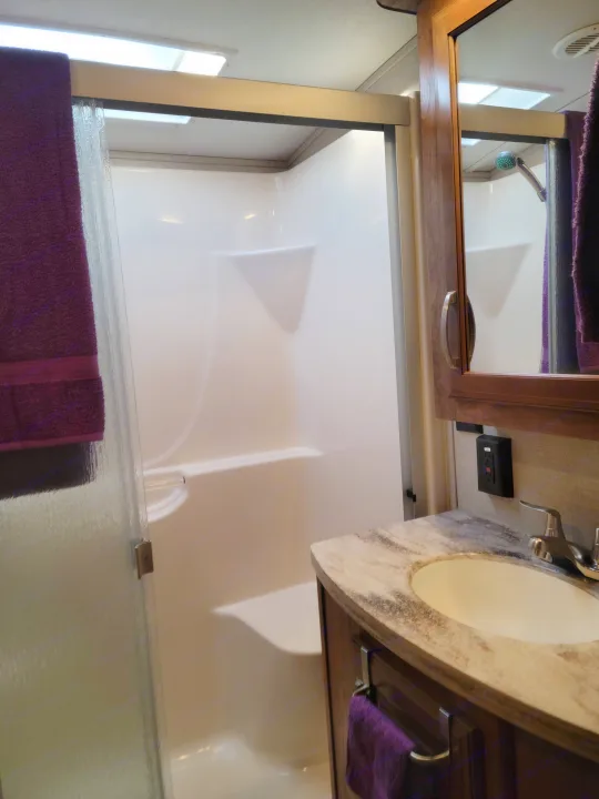 Inside an RV rental: a modern, compact bathroom with a shower and vanity with a sink.. Keystone Montana 2017