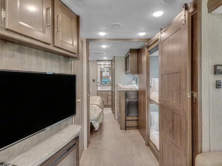 Spacious RV rental interior featuring a bedroom, bunk beds, kitchen, and bathroom for comfortable travel.. Coachmen Mirada 2021