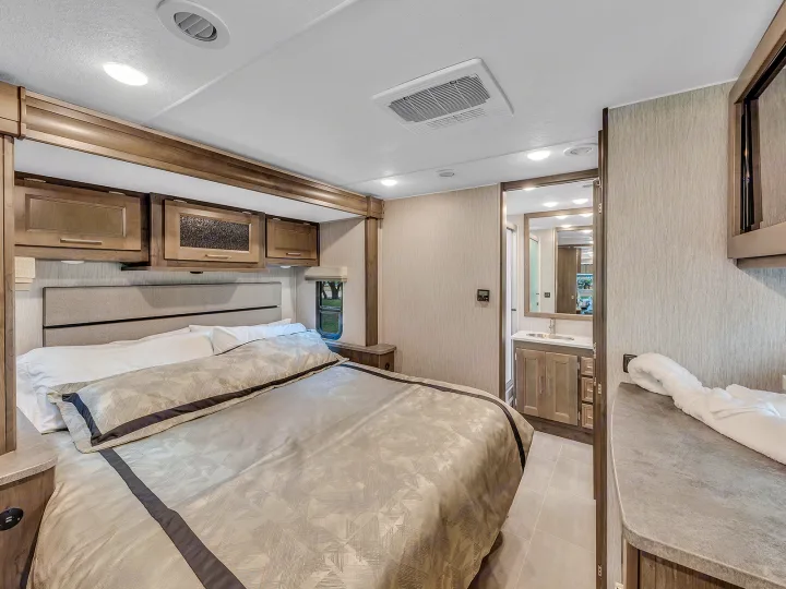 Experience comfort in this RV rental's modern bedroom. Features a large bed, cabinets, and a private bathroom.. Coachmen Mirada 2021