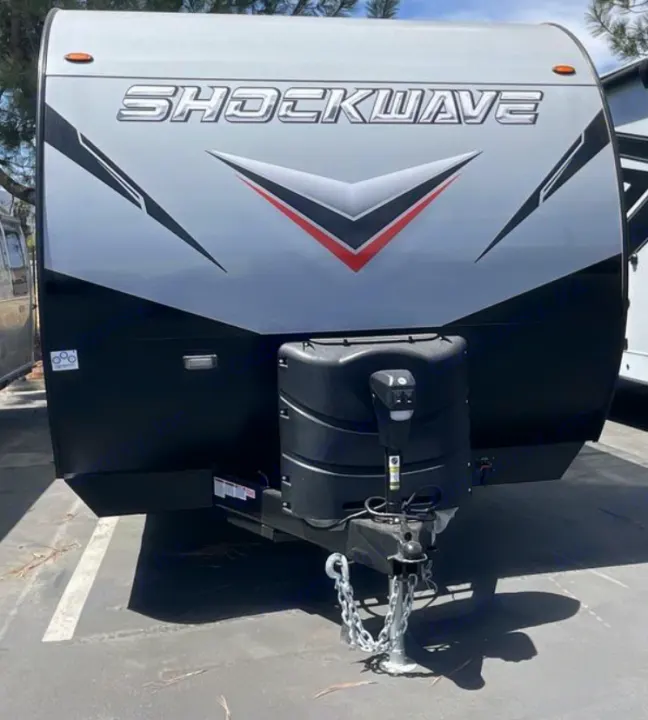 Front of a gray and black Shockwave travel trailer, ready for rv rental. Propane tank and hitch visible.. Forest River Shockwave 2022