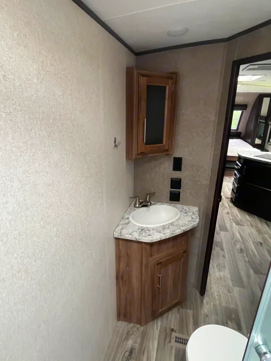 RV rental: Interior shot of a compact bathroom vanity with a sink, wooden cabinets, and textured light flooring.. Jayco White Hawk 2018