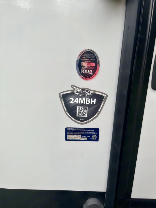 Essential RV rental details: RVIA, 24MBH model, and Washington state compliance stickers on a travel trailer.. Jayco White Hawk 2018