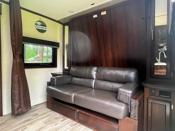 RV rental interior: features a dark brown leather sofa, window, and hidden wall bed for optimized space.. Jayco White Hawk 2018