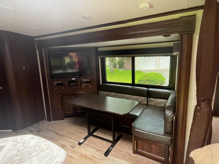 Spacious RV rental dinette and entertainment area with comfy seating and scenic window view.. Jayco White Hawk 2018