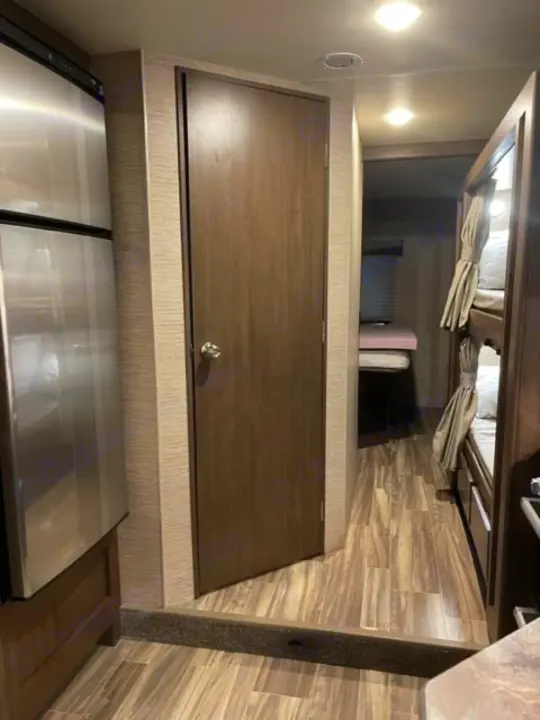 RV rental interior: stainless steel fridge, a privacy door, and cozy bunk beds maximize compact living space.. Thor Four Winds 2022