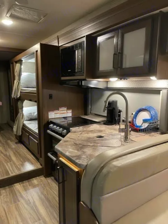 Explore an RV rental's well-equipped kitchen with microwave & sink, plus cozy bunk beds & a dinette for comfy travel.. Thor Four Winds 2022